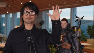 Hideo Kojima waving near a Sam Porter Bridges statue