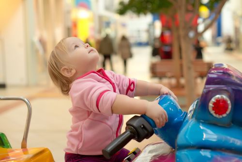 A small child rides on a ride at a mall