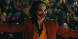 Joker smiling and bloody, surrounded by followers