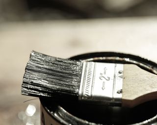 paint brush on top of an opened can of paint