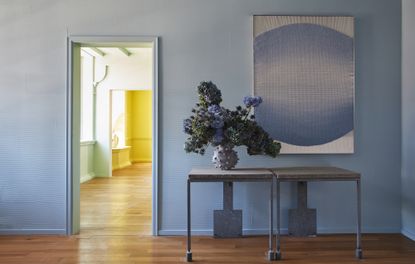 A blue entryway with a console table and wall art