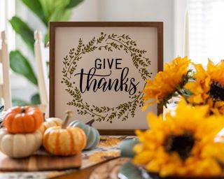 thanksgiving decor including a sign and flowers on a table