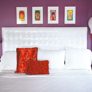 bedroom with purple wall and bedding with red cushions