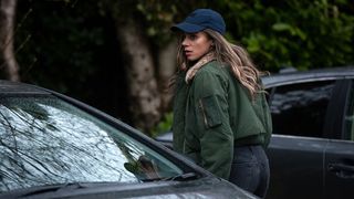 Woman standing next to car, looking worried