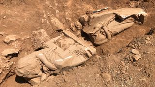 Two headless statues discovered at an ancient Greek burial site depict a dead woman in a seated position and possibly her servant.
