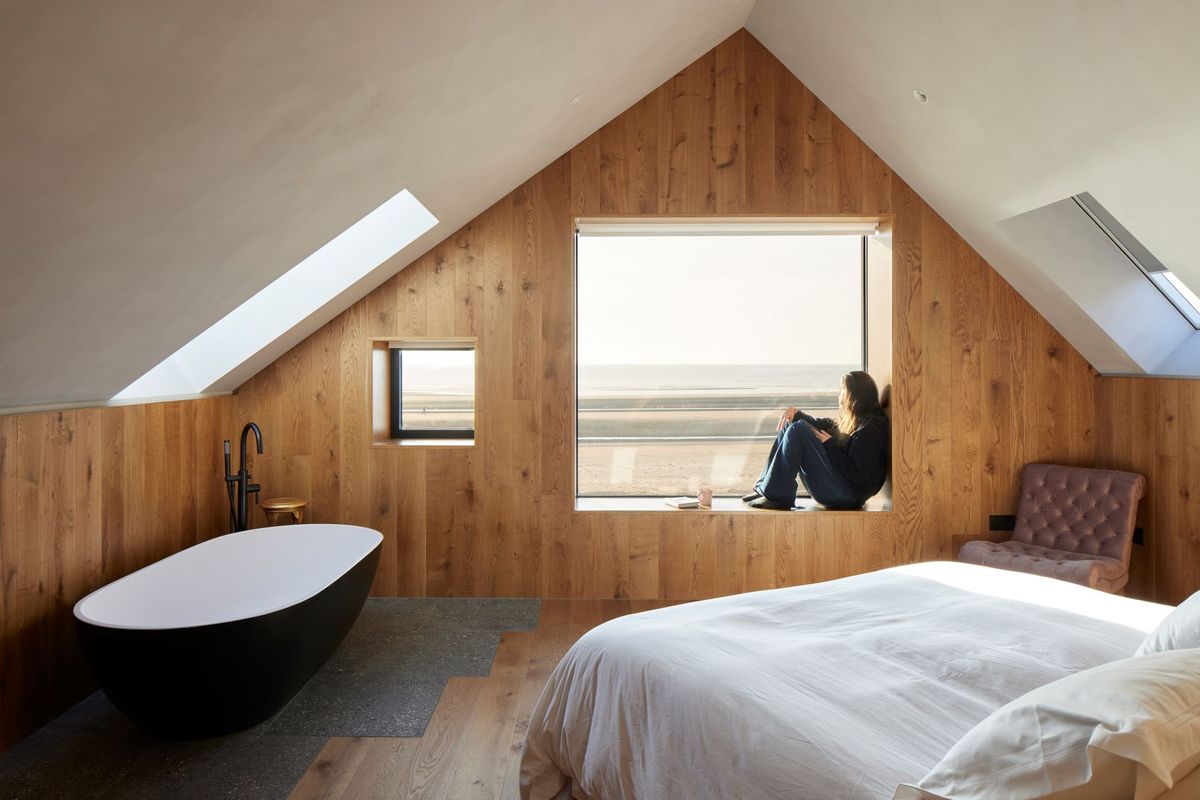 The bedroom with a bath inside it and wood panelled walls and floors