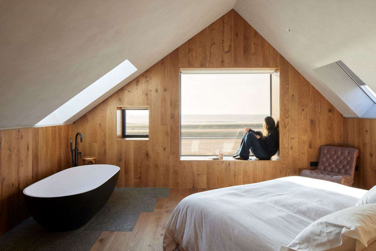 The bedroom with a bath inside it and wood panelled walls and floors