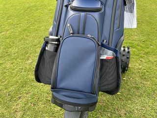The snap closure drinks holders on the Vessel Lux XV 2.0 cart bag holding a larger water bottle and a small can