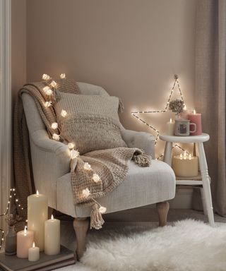 A gray armchair next to a side table, with fairy lights around it