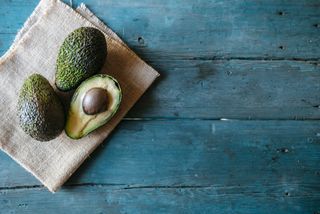 Whole and halved avocado on wooden table