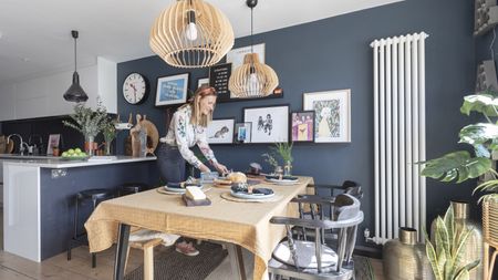 A dark painted kitchen-diner with gallery wall and large pendant lights 