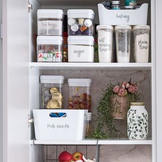 Inside of a food storage cupboard with food stored in labelled clear containers