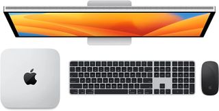 Bästa tillbehör till Mac mini M2: En Mac mini, en tangentbord, en mus och en skärm mot en vit bakgrund.