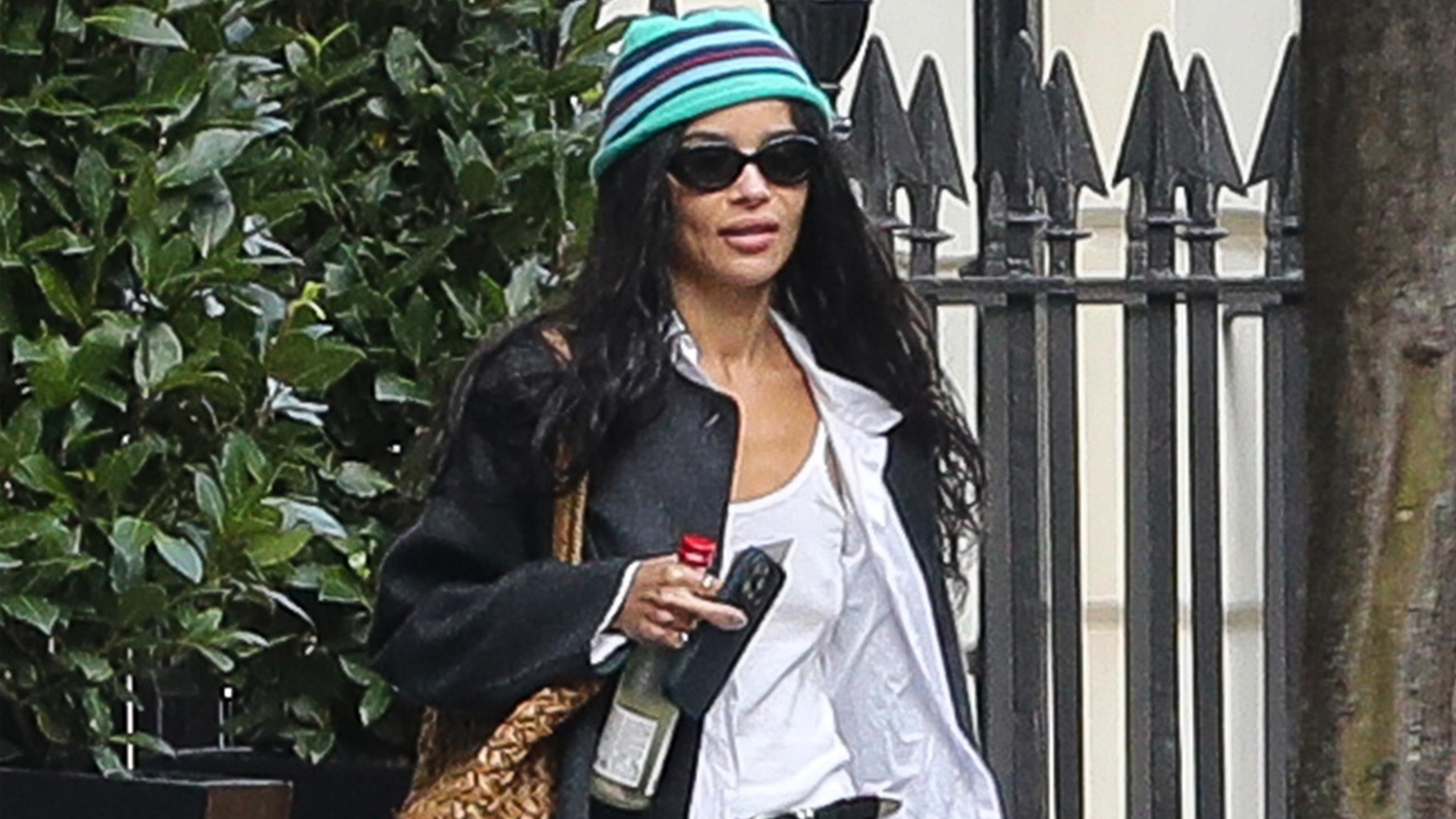 zoe kravitz wears a stripe hat, black jacket, and a white tte.