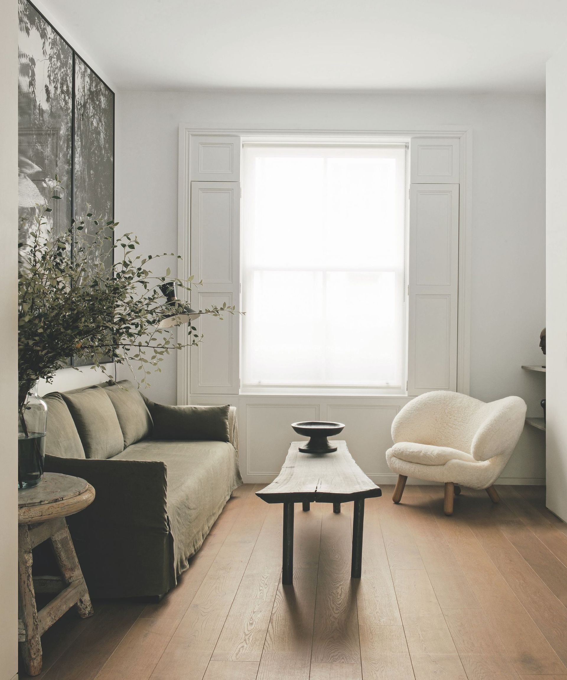 Minimal living room with boucle armchair, linen sofa, white wall and wood coffee table