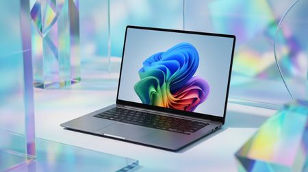 A sleek laptop with a vibrant abstract design on the screen, surrounded by colorful geometric shapes and reflections.
