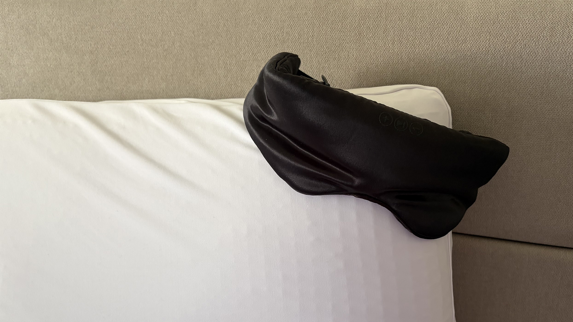 The SilkSound Sleep mask balanced on the edge of a pillow in the reviewer's bedroom