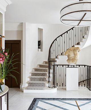 Traditional, large white entryway with curved staircase, classical sculpture on table,