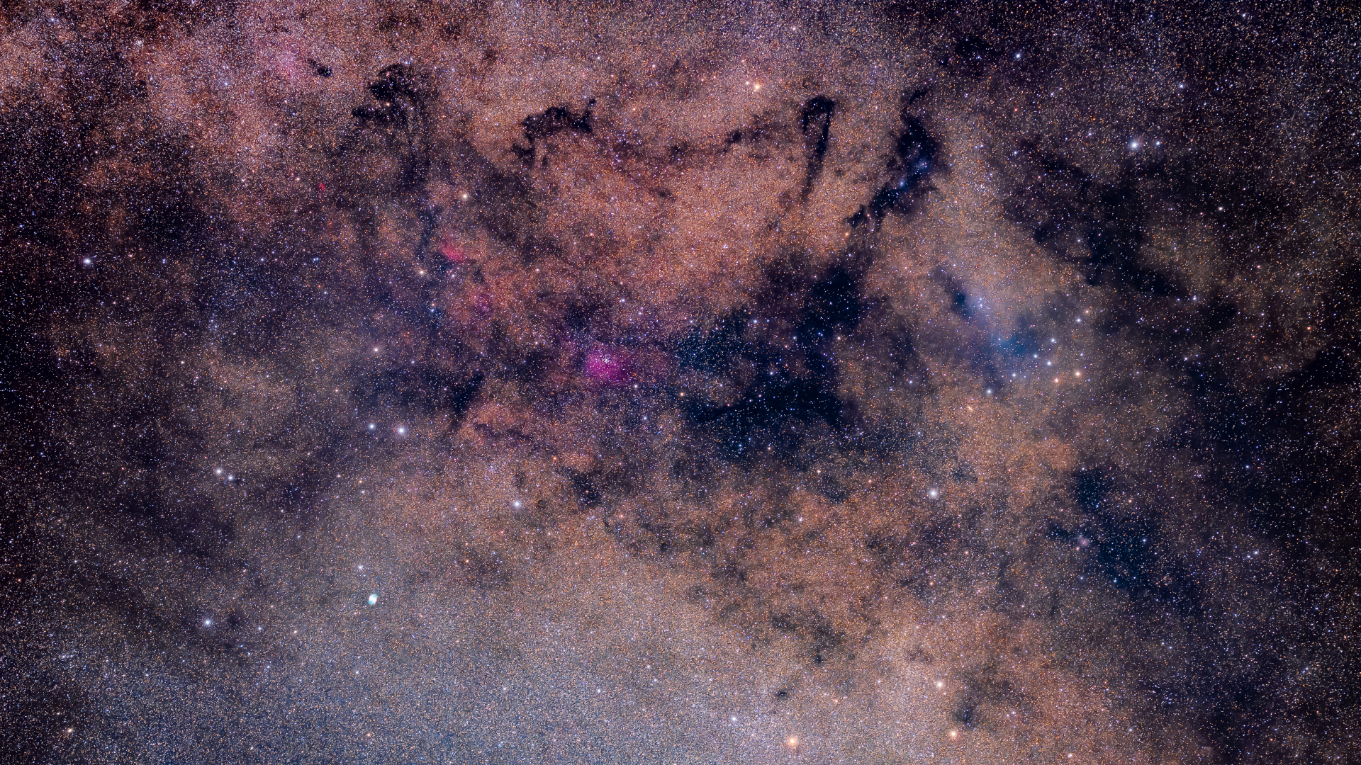 A deep space image showing the dense starfields and swirling interstellar clouds of the Milky Way.