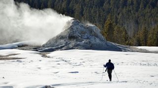 a skier moves through a geyser basin in Yellowstone National Park