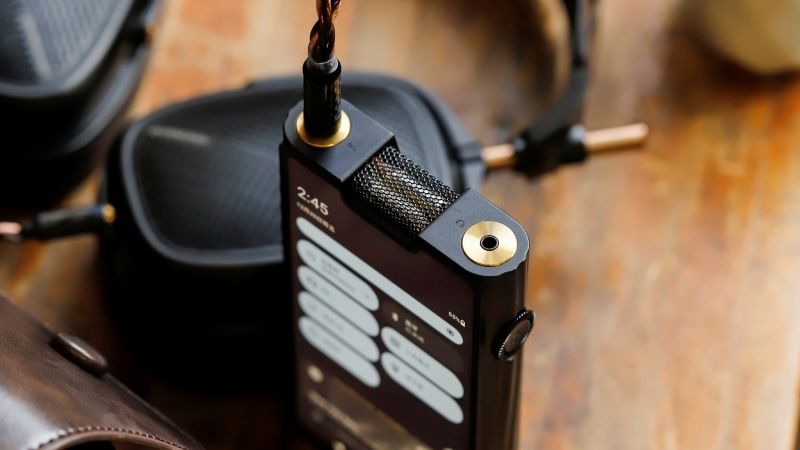 Shanling M8T Hi-Res Music Player laid out on wooden table, with black headphones nearby.