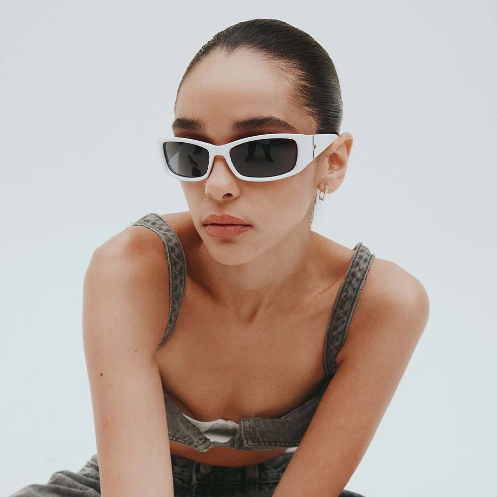 A woman wearing a pair of white sunglasses from Le Specs 