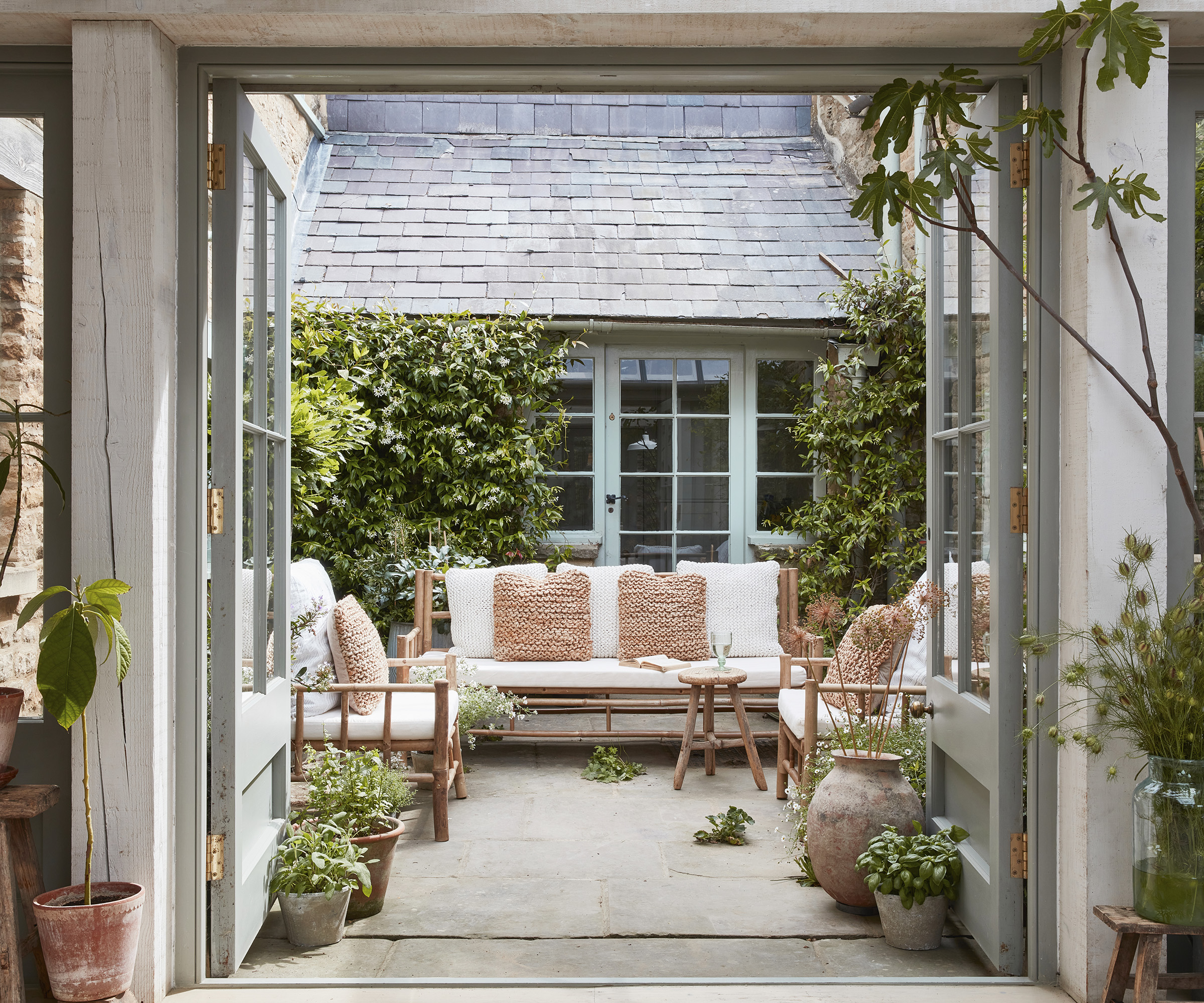 A beautiful courtyard garden with wooden and linen garden bench with cushions