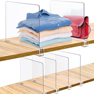 Clear plastic shelf dividers on wooden shelves, seperating folded shirts and a bag