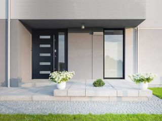 Blue Kloeber UberFront door below a large roof overhang above, on the front of grey contemporary self build