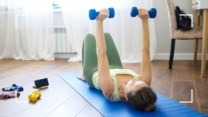 Woman using dumbbells and one of the best strength training apps with a yoga mat to work out at home