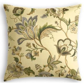 A light yellow throw pillow with green and blue floral patterns
