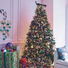 Colourful Christmas tree in living room with peacock as tree topper.