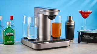 the bartesian premium cocktail machine photographed against a blue background showing its drink-making abilities and accessories and functionality with cocktail pods