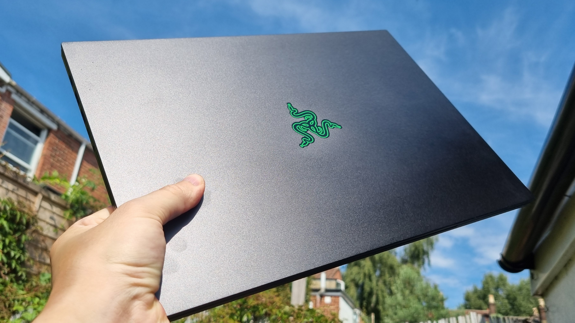 A Razer Blade 16 gaming laptop being held up to the sky