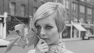 English model, actress, and singer Twiggy holds a maple leaf while standing in the middle of King's Road in Chelsea, London, UK, 13th June 1966.