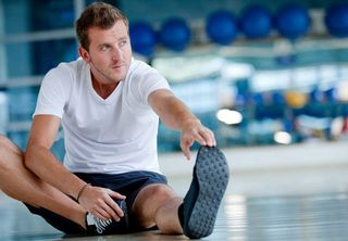 Man at the gym doing stretching exercises and smiling on the floor 
