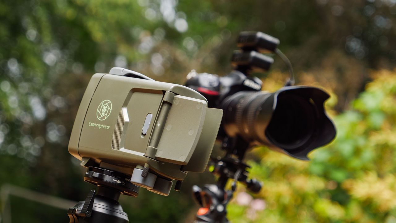 Camtraptions Camera Trap device outdoors alongside a Nikon DSLR camera