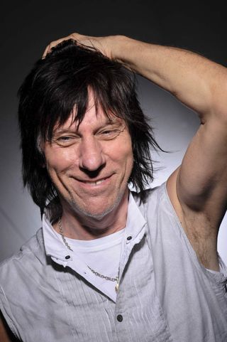 Jeff Beck scratching his head and smiling (studio portrait)