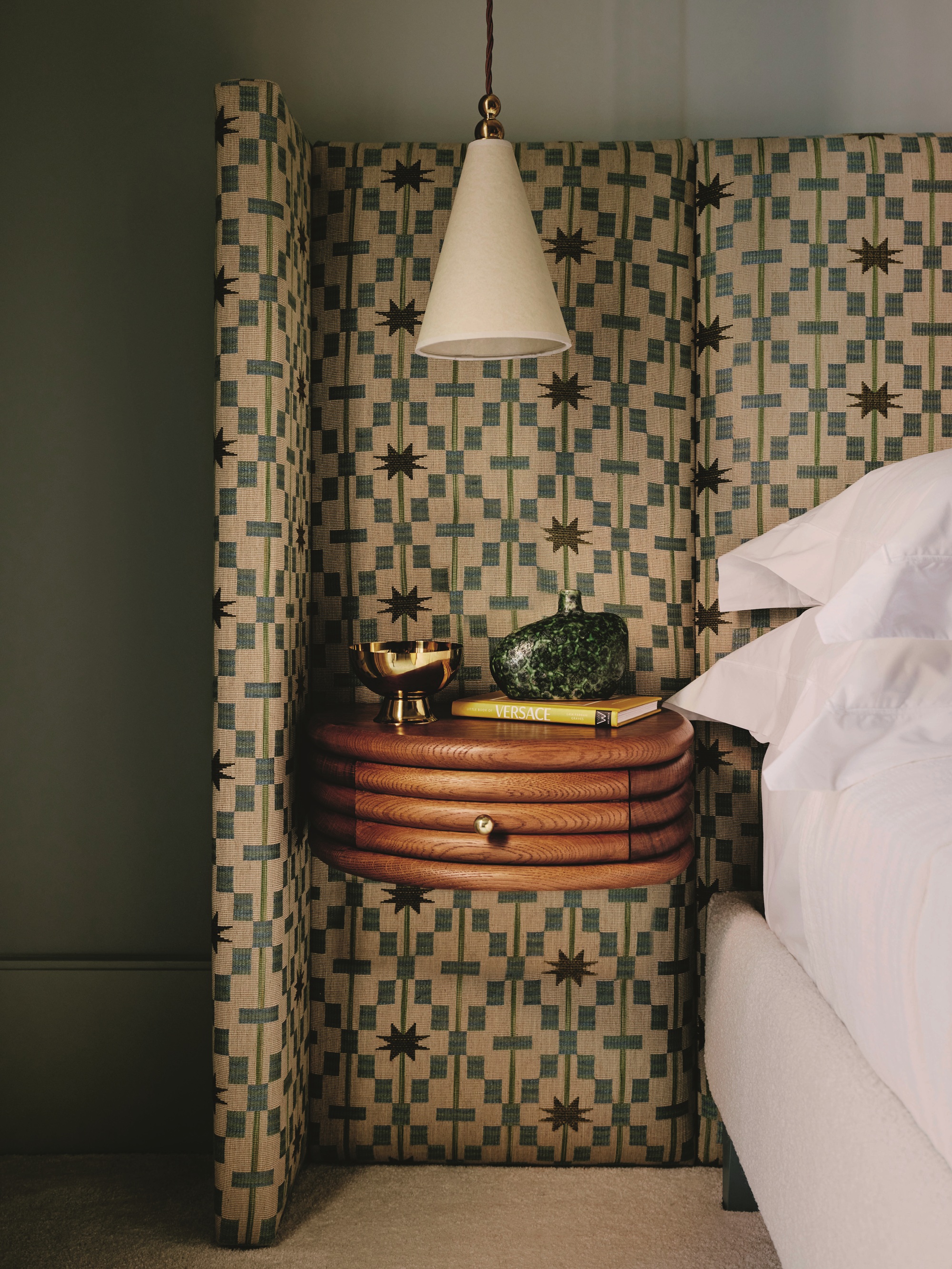 a wrap around headboard in green patterned fabric with a floating bedside table drawer