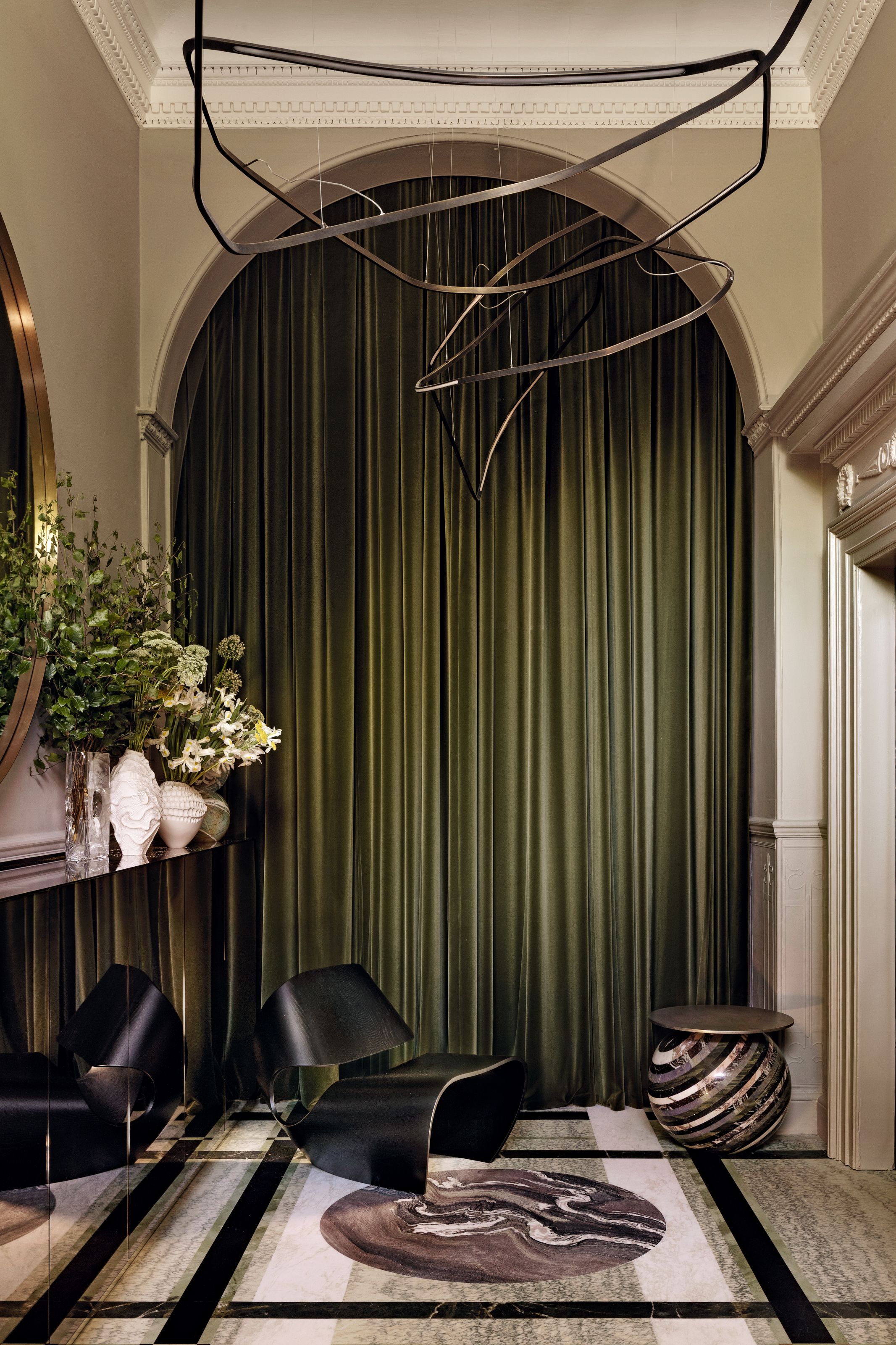 Roisin Lafferty's new gallery &amp;ndash; featuring a sculptural black chair and side table in front of a deep olive green velvet curtain