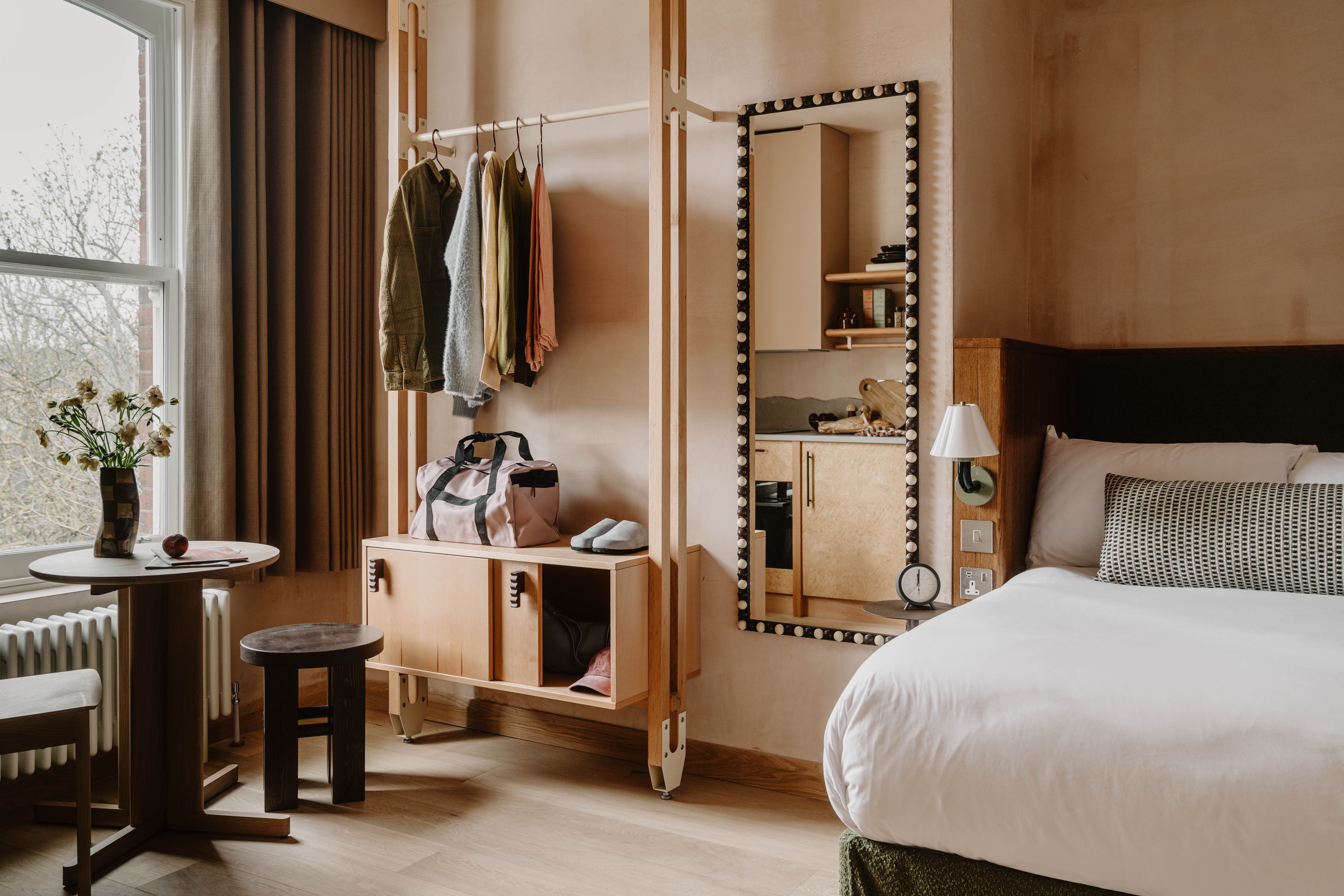 A neutrally tinted hotel with argilla-toned walls, sculptural furnishings, wooden surfaces, and curated art and tilework.