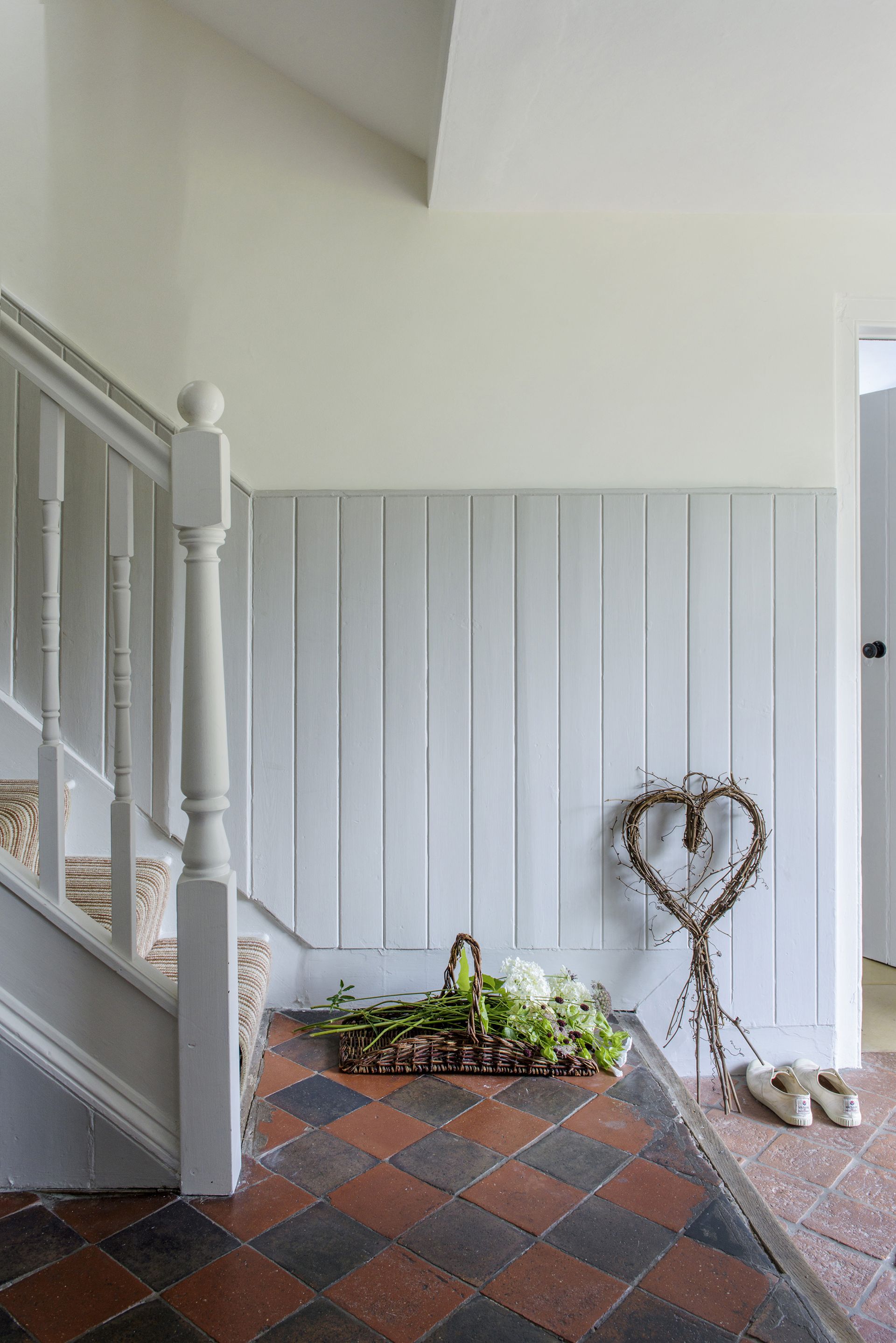 Hallway with Victorian floor tiles, staircase with a basket of flowers at the bottom