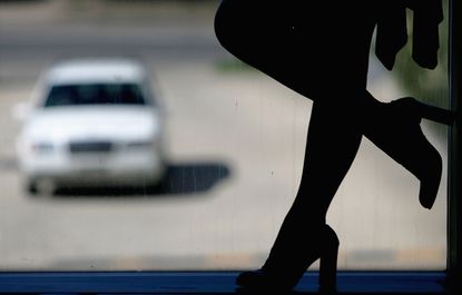 A prostitute stands outside a car
