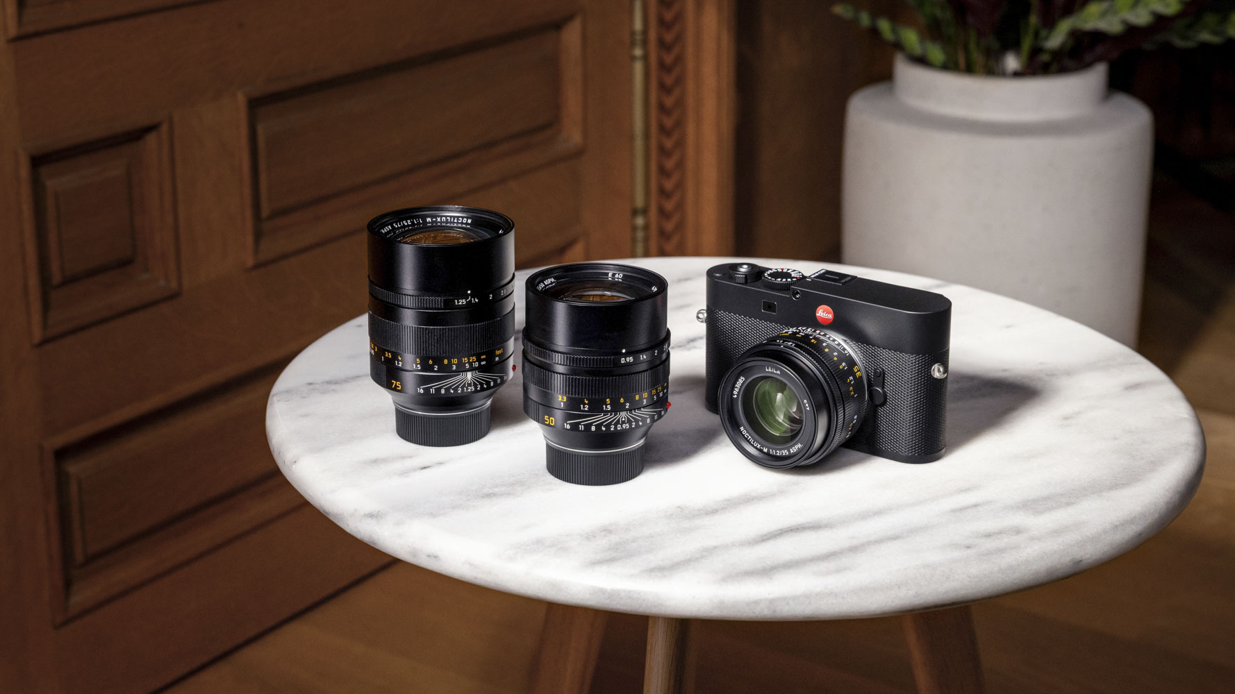 Leica Noctilux-M 35 f/1.2 ASPH lens attached to a Leica camera on a marble table, alongside 50mm and 75mm ASPH Leica lenses