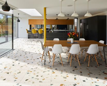 A kitchen with terrazzo floor tiles and warm wooden and black cabinetry