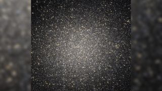 Globular cluster Omega Centauri is a dense region of stars against a black background.