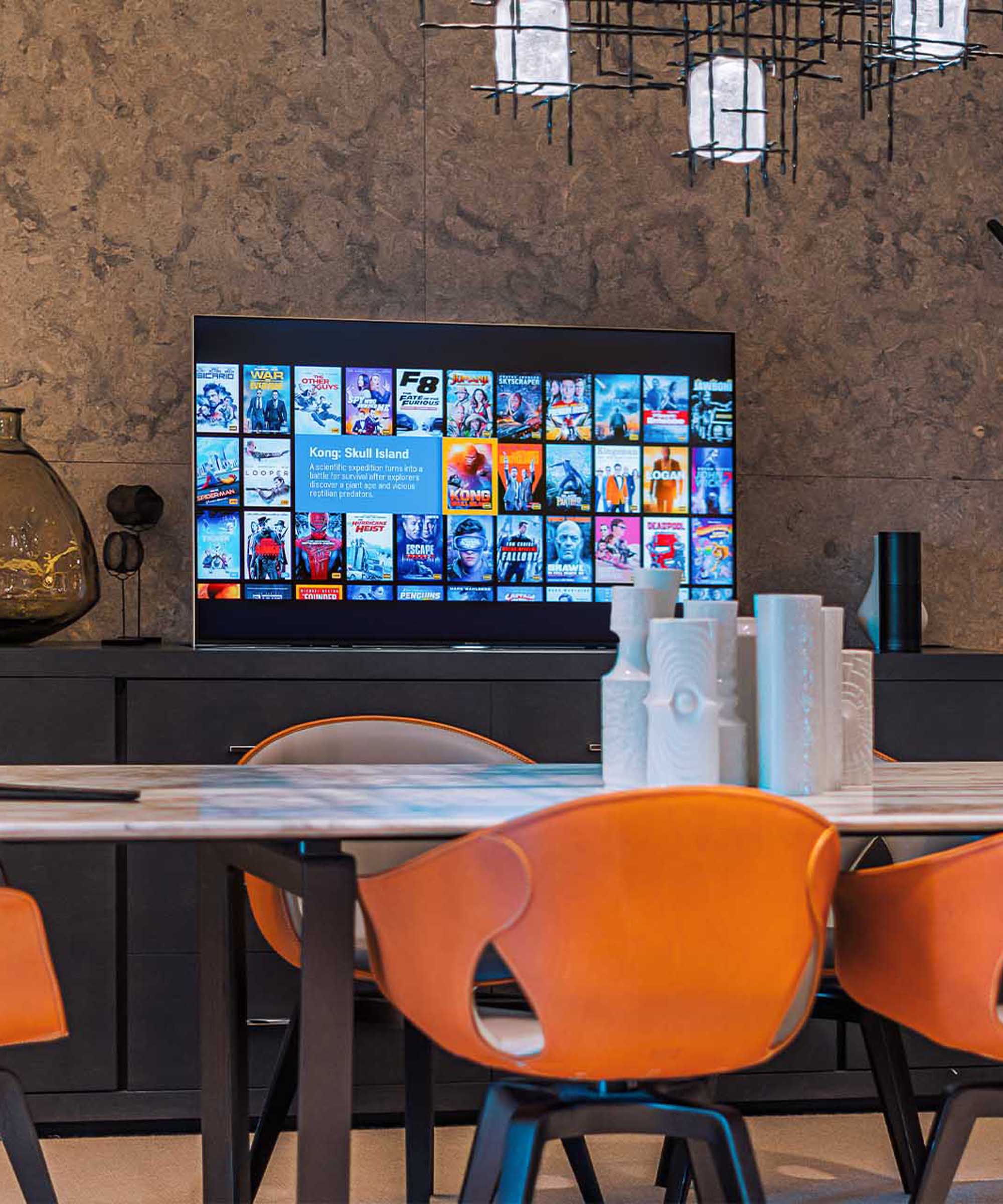 TV popping out of a panel in a luxury dining area with orange dining chairs and marble top table