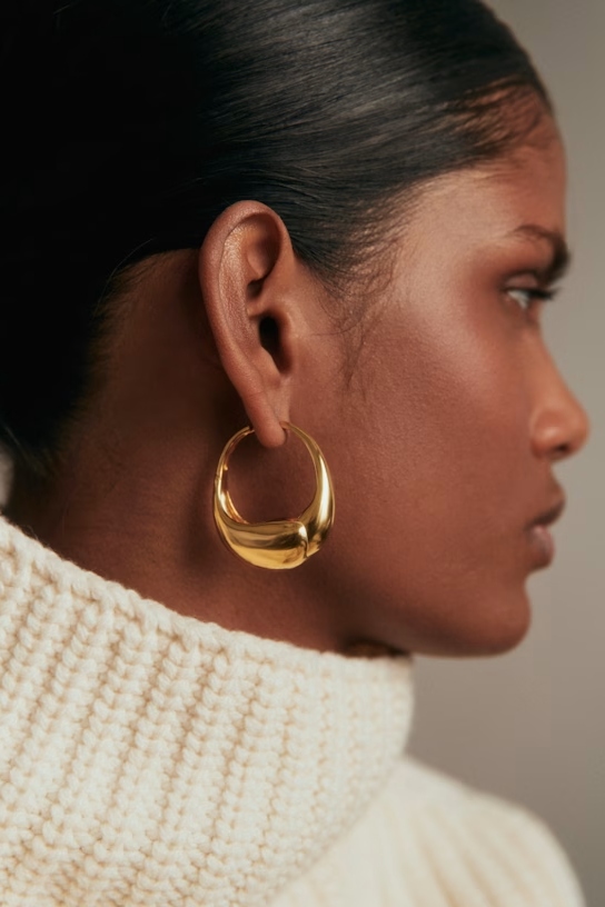 A model wearing gold hoop earrings.