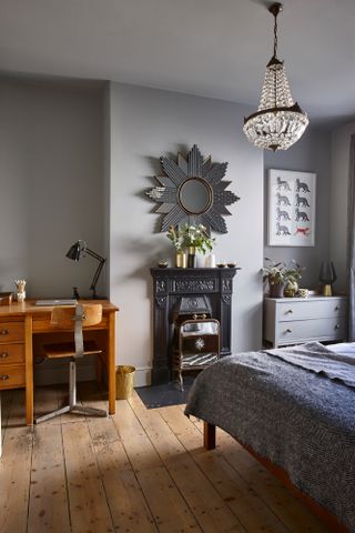 Jason Traves house: Bedroom with light grey painted walls, black Victorian hearth with star mirror above, and chandelier