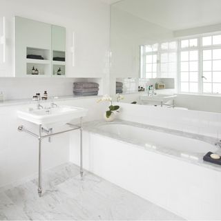 white marble bathroom with wash basin and bathtub